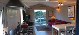 cocina y sala de estar con sofá rojo y mesa en Chalet 47m2 dans PRL linge fourni, en Gujan-Mestras