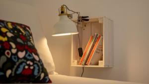 una lámpara sobre una cama con libros en The Alfama Apartment, en Lisboa