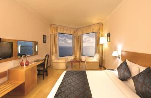 ein Hotelzimmer mit einem Bett und einem Schreibtisch in der Unterkunft The Quilon Beach Hotel and Convention Center in Kollam