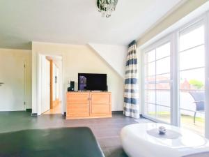 a living room with a tv on a wooden dresser at De Möhlenkieker 4 in Greetsiel