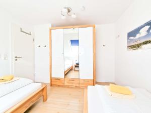 ein weißes Zimmer mit einem Spiegel und einem weißen Sofa in der Unterkunft De Möhlenkieker 4 in Greetsiel