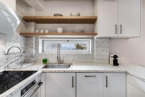 a kitchen with white cabinets and a sink and a window at Vouliagmeni Stylish Homes by BluPine in Athens
