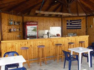 un restaurante con un bar con mesas y sillas en Achillion Hotel en Skála Potamiás