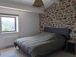 1 dormitorio con cama y pared de piedra en La Grange, Gîte 4 à 6 pers avec vue en Saint-Just-près-Brioude