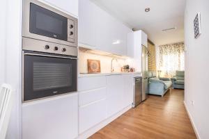 eine Küche mit weißen Schränken und einem TV über dem Ofen in der Unterkunft Apartamento Leyendas de Becquer A4 in Sevilla