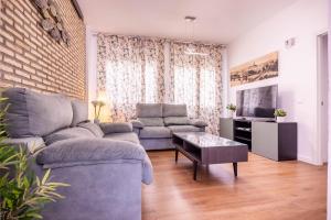 ein Wohnzimmer mit einem Sofa und einem TV in der Unterkunft Apartamento Leyendas de Becquer A4 in Sevilla