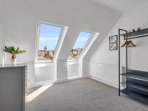 an attic room with two windows and a staircase at Pass the Keys Large Terraced Home In the City in Canterbury