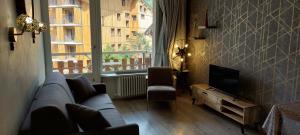 - un salon avec un canapé, une télévision et une fenêtre dans l'établissement Le Rosset, à Tignes