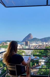 una donna seduta a un tavolo con vista sulla città di Casa Do Gato Cinzento a Rio de Janeiro