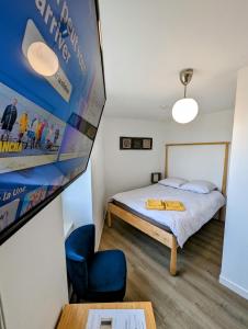 a small bedroom with a bed and a blue chair at Concept Appar't Hôtel - 201 in Saint-Brieuc