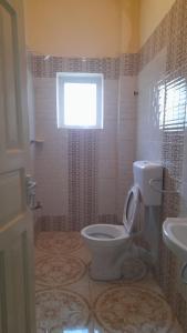 a bathroom with a toilet and a window and a sink at Crown Apartments in Malindi