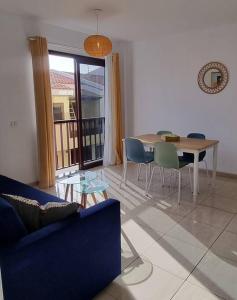 a living room with a blue couch and a table and chairs at Appartement calme à 200 m de la mer avec ascenseur in Alcalá