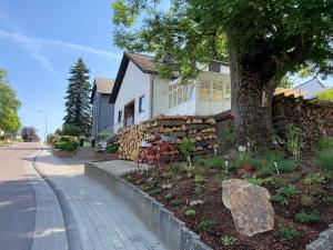 ein weißes Haus mit einem Baum und einer Steinmauer in der Unterkunft Ferienwohnung Rosengarten in Osburg