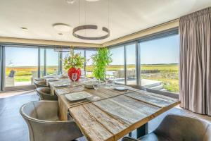 a dining room with a long wooden table and chairs at Natuurvilla 18 Waswaal in De Waal