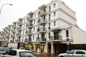 biały budynek z zaparkowanymi przed nim samochodami w obiekcie D Apartments Centrum Powietrze w mieście Białystok