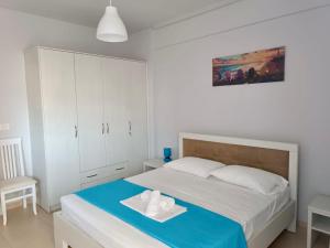 1 dormitorio blanco con 1 cama con manta azul en AQUATIC Apartments Sarande, en Sarandë