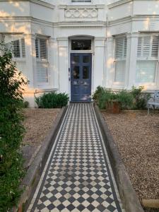 a white house with a blue door and a checkered floor at Contemporary beach apartment in Brighton & Hove