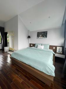 a bedroom with a large bed and a wooden floor at Kaylin House in Xuan An