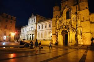 a large building with people walking in front of it at night at Casa Coelho Guesthouse in Coimbra