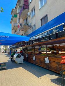 a food stand with a blue awning in front of a building at Апартаменты Инал-ипа 10 in Sukhum