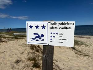 a sign on a wooden post at the beach at Albatross_resort_alejaa in Ķesterciems