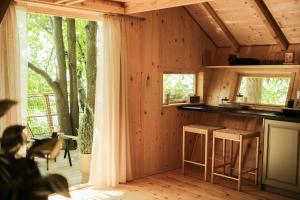 a kitchen with wooden walls and a large window at TREEHOUSE POD LESOM in Muráň
