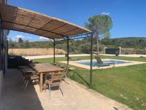 een patio met een tafel en stoelen en een zwembad bij Provencelia in Pernes-les-Fontaines