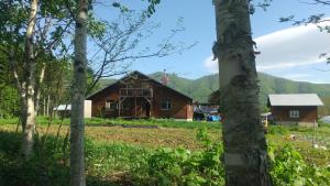 Ski base في Akaigawa: منزل في الغابة مع جبال في الخلفية