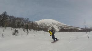 a person riding a snowboard down a snow covered slope at Ski base in Akaigawa