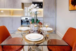une salle à manger avec une table et des chaises en verre dans l'établissement Marble Arch Suite 6-Hosted by Sweetstay, à Londres