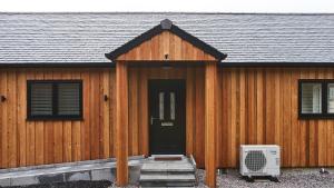 a wooden house with a door and a fan at Shoreland Lodges - Cherry Lodge in Fort Augustus