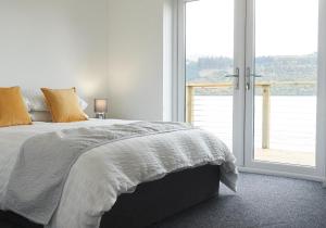 a white bedroom with a bed and a large window at Shoreland Lodges - Cherry Lodge in Fort Augustus