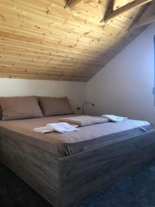 a large bed in a room with a wooden ceiling at Aqualux apartments in Vrdnik