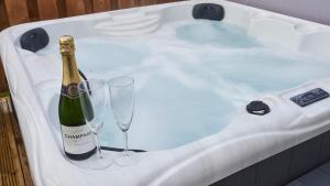 a bottle of champagne and two glasses in a bath tub at Shoreland Lodges - Holly Lodge in Fort Augustus