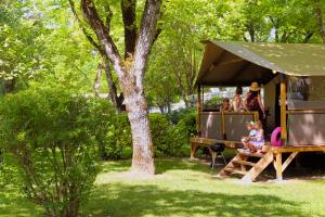 a group of people sitting on a picnic table in a tent at Camping Moulin de Paulhiac in Daglan