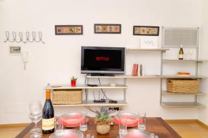 una mesa con copas de vino y una TV en la pared en Aosta Centro Storico - Les Cretes Apartment Netflix & Relax, en Aosta