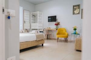 Un dormitorio con una cama y una silla amarilla. en Villa Sece - Luxury Rooms, en Agrigento