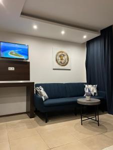 ein Wohnzimmer mit einem blauen Sofa und einem Flachbild-TV in der Unterkunft Privat Apartament Marina City in Baltschik