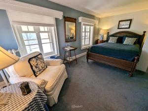 een slaapkamer met een bed, een bank en een stoel bij Cromwell Manor Inn in Cornwall-on-Hudson