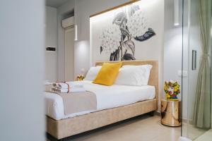 um quarto com uma cama com lençóis brancos e almofadas amarelas em Villa Sece - Luxury Rooms em Agrigento