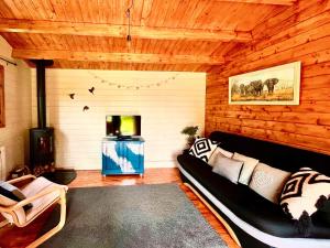 a living room with a black couch and a tv at Willow Lodge in Buckhorn Weston