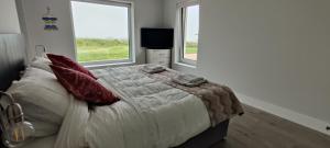 a bedroom with a large bed with two windows at Fal Mor House in Belmullet