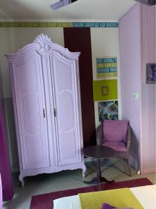 une armoire rose dans une chambre avec une chaise et une table dans l'établissement B&B Binot, à Carmagnole