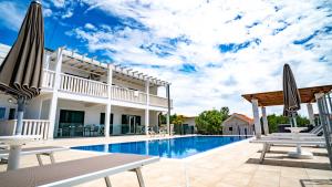 einen Pool mit Stühlen und Sonnenschirmen neben einem Haus in der Unterkunft Calma apartments in Trogir