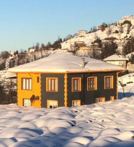 ein gelbes Haus mit einem schneebedeckten Dach in der Unterkunft Kemer konak in Cayeli