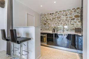 a kitchen with a stone wall and a counter with stools at Petit loft de charme proche VERSAILLES SACLAY 30 mn PARIS jardin terrasse parking securisé in Janvry