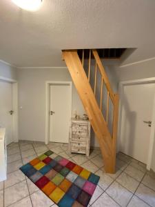 Habitación con escalera de madera y alfombra colorida. en Ferienwohnung Halen Landkreis Cloppenburg, 