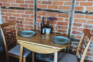 Cosy character cottage in central Marlborough UK في مارلبوره: طاولة خشبية وصحنين زرقاء وجدار من الطوب