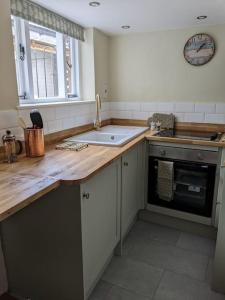 uma cozinha com um lavatório e uma bancada em Cosy character cottage in central Marlborough UK em Marlborough