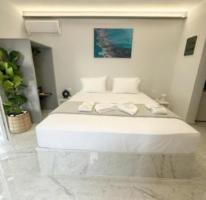 um quarto com uma grande cama branca com toalhas em Mora Houses em Mandrakia